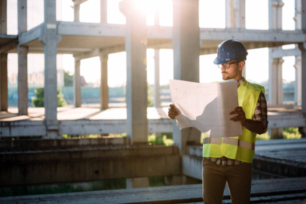 portrait of male site contractor engineer with hard hat holding blue print paper - protective workwear hat violence construction imagens e fotografias de stock