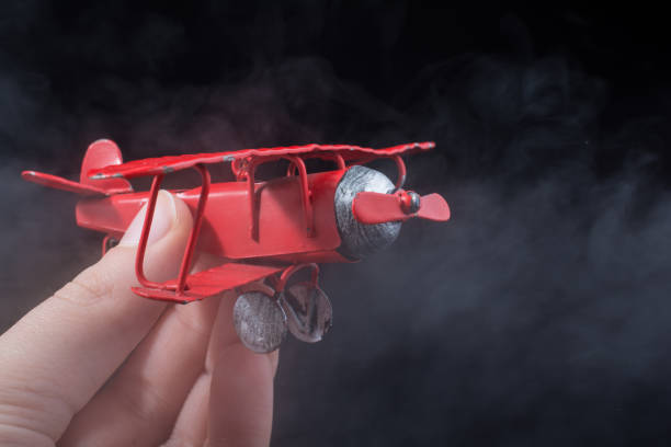 istock Hand holding a toy plane on black background 1011961726