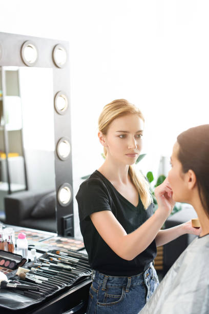 istock selective focus of young woman getting makeup done by makeup artist 1011965054