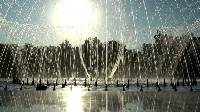 Dancing fountain in the city Park at sunset. Water jets fly into the sky in the rhythm of music against the background of the sun in the city Park.