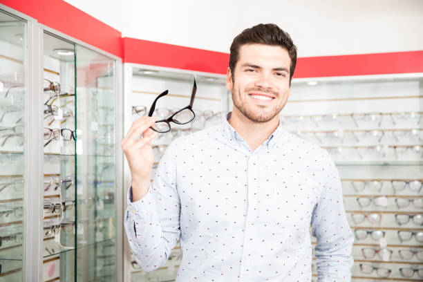 istock Attractive man holding black frame eyeglasses at optical store 1011969616