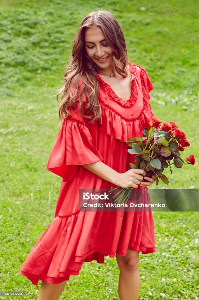 Joven Feliz Hermosa Mujer En Vestido Rojo Bailando Sobre El Pasto Verde Y  Con Ramo De Rosas Rojas Foto de stock y más banco de imágenes de Adulto -  iStock