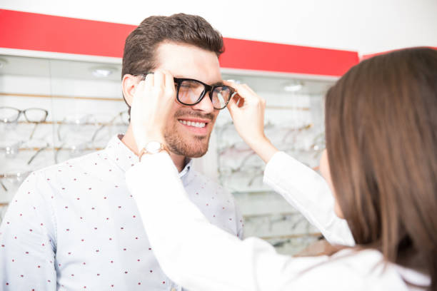 istock Handsome man and professional optician helping man to choose spectacles 1011971364