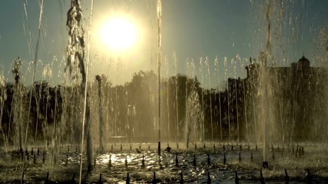 General view of the city fountain at sunset. Streams of water fly into the sky in the rhythm of music on the background of a yellow sunset in the city Park.