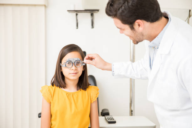 istock Handsome optician checking girl eyes using trial frame in optical store 1011971708