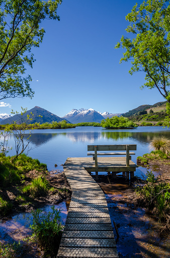Tranquil scene at Glenorchy, New Zealand with bench and footpath visible at the at the lake.