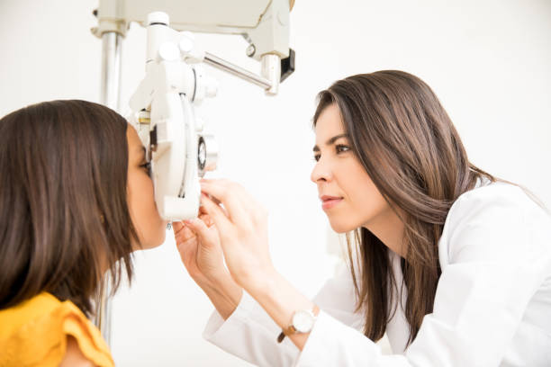 Optometrist doing sight testing for school girl patient Pretty optometrist adjusting phoropter for child patient in store eye test equipment stock pictures, royalty-free photos & images