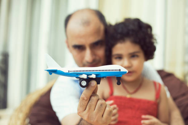 Excited girl and father playing with toy airplane at home
