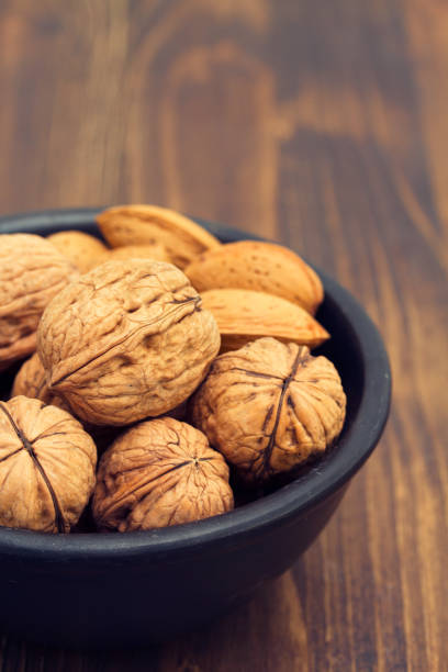 istock walnuts and almond on black bowl on wooden background 1011983068