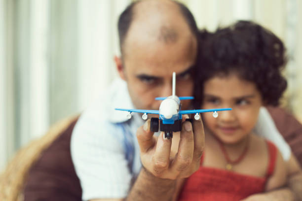 Excited girl and father playing with toy airplane at home