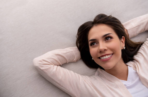 Portrait of a thoughtful woman relaxing at home lying on the couch and smiling - lifestyle concepts
