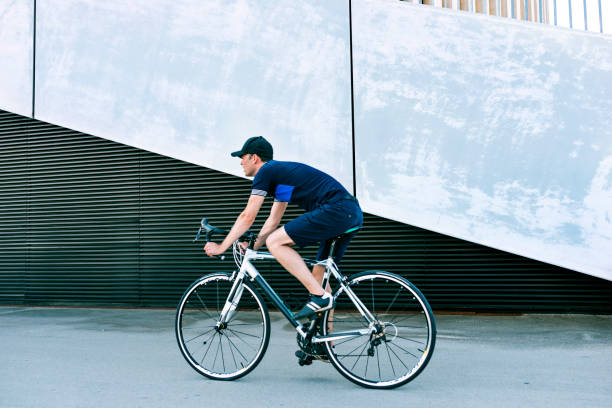 istock Man rides racing bicycle on road next to big concrete wall 1012004868