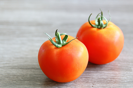 Fresh red tomatoes on a board over a light grey background