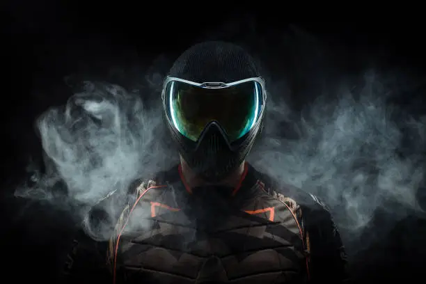 a paintball player stands in the dark with fog