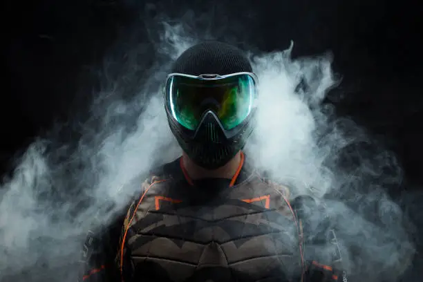 a paintball player stands in the dark with fog