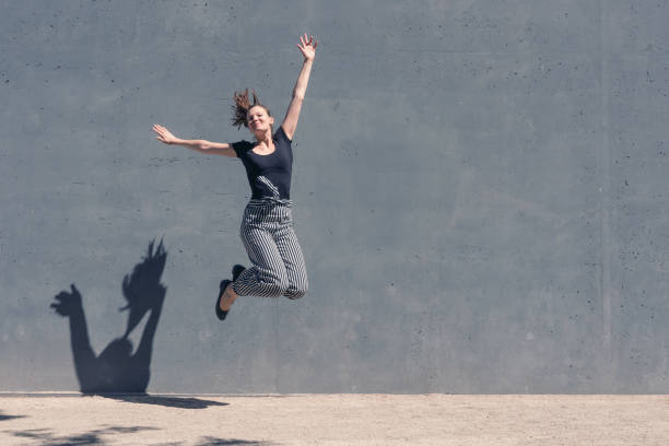 istock Young jumping woman in front of a concrete wall 1012013724