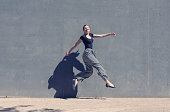 Young jumping woman in front of a concrete wall