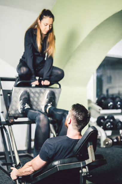 istock Young handsome man with his girlfriend exercise legs in the gym. 1012026898