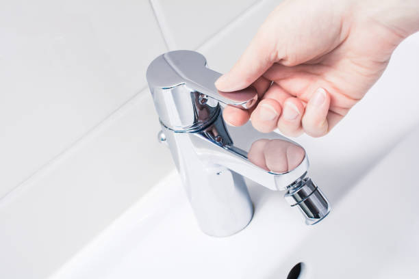 Female Hand On The Handle Of A Chrome Faucet, Ready To Turn On Water stock photo