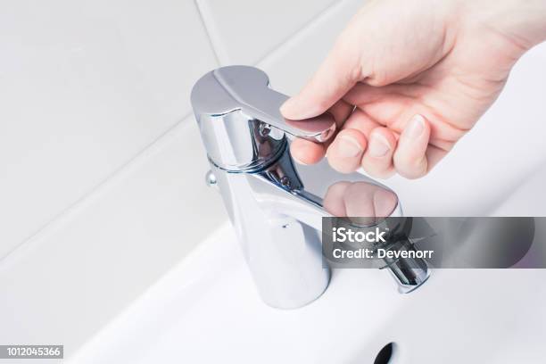 Female Hand On The Handle Of A Chrome Faucet Ready To Turn On Water Stock Photo - Download Image Now