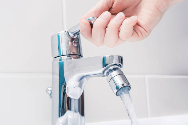 Female Hand On The Handle Of A Chrome Faucet With Running Water stock photo
