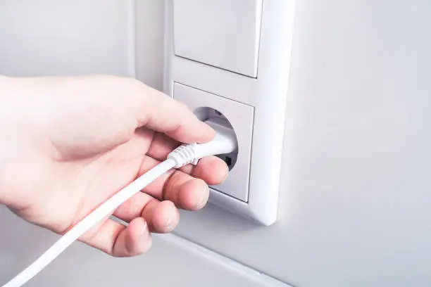 Pulling An Electrical Plug Out Of A Wall Socket, An Energy Saving Concept