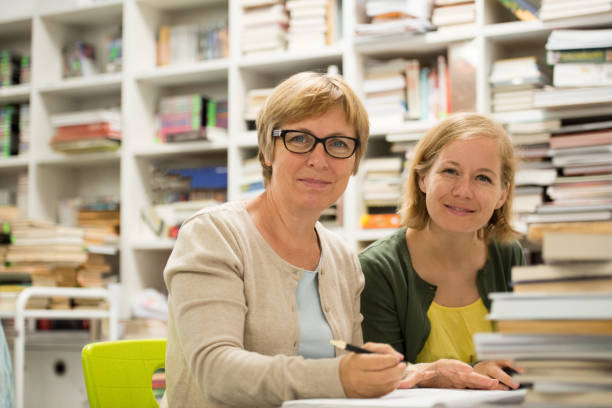 istock Two mature college women students studying at table in a new library 1012048054
