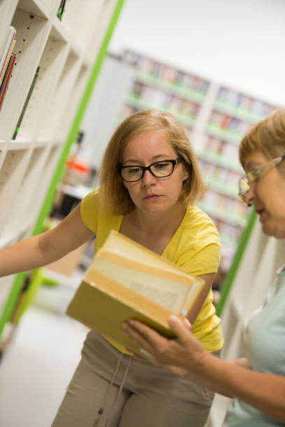 istock Two mature college women students studying in library 1012051262
