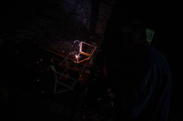 Welder welding metal in workshop with sparks