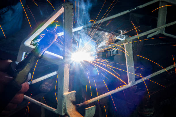 istock Welder welding metal in workshop with sparks 1012063312