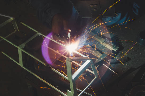 istock Welder welding metal in workshop with sparks 1012064064