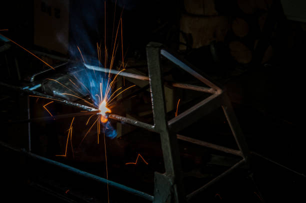 istock Welder welding metal in workshop with sparks 1012064250