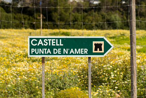 Signpost that leads to a hiking trail to the old Castell Defense tower of Punta de N'Amer at Sa Coma, Mallorca, Spain