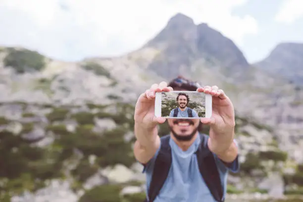 Photo of Tourist man taking selfie in the mountain