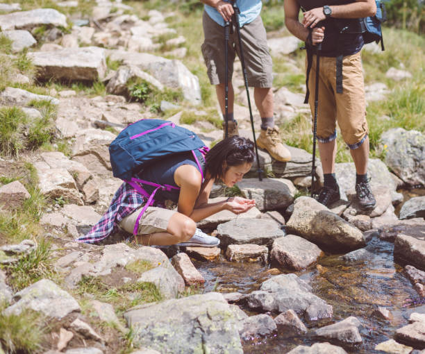 istock Thirsty hiker drinking water from the stream 1012080538