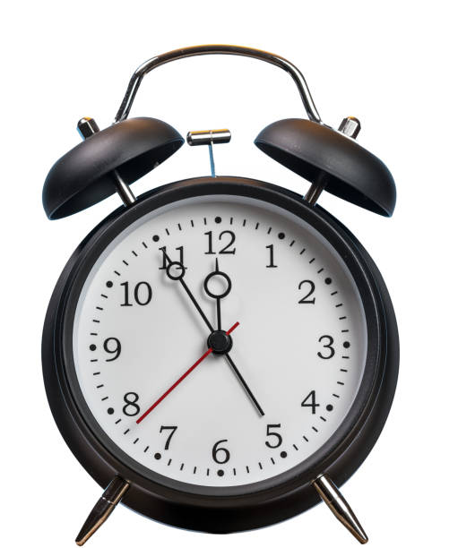 istock Alarm clock approaching midnight and isolated against white 1012084462