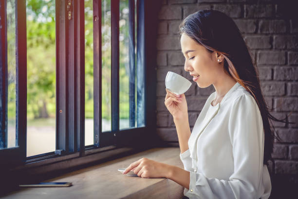 istock Side View Of Woman Drinking Coffee While Sitting At Table 1012094490