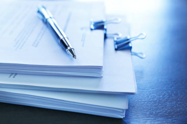 Ballpoint Pen Resting On Top Of Stack Of Documents A ballpoint pen rests on top of a stack of documents ready for signing. The image is photographed using a very shallow depth of field with the focus being on the tip of the pen. legal document stock pictures, royalty-free photos & images