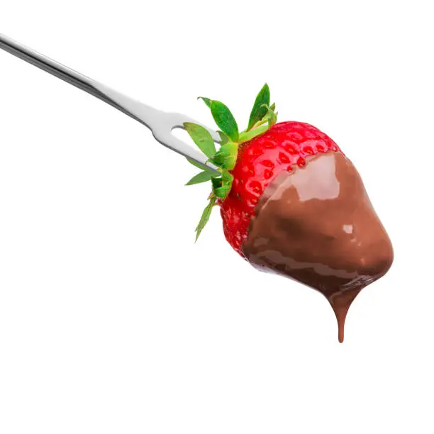 Fondue strawberry soaked in hot black chocolate on a fork isolated on white background