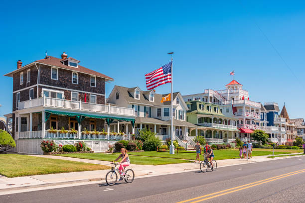 People in Cape May New Jersey USA People bike and walk in front of traditional villas in Cape May, New Jersey, USA, on a sunny summer day. new jersey photos stock pictures, royalty-free photos & images