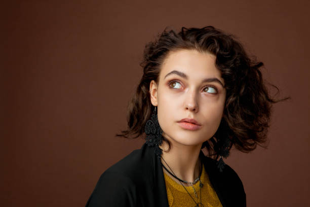 retrato do close-up de uma jovem mulher bonita com cabelo encaracolado no estúdio em um fundo marrom - adult caucasian curly hair human face - fotografias e filmes do acervo