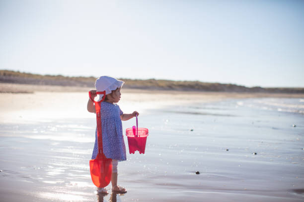 istock baby girl playing at summer beach 1012185874
