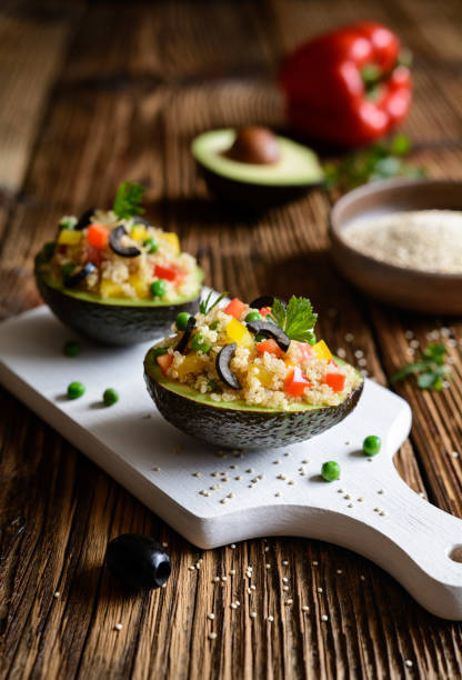 avocado ripieno di quinoa, piselli verdi, pomodoro, olive, peperone e prezzemolo - stuffed stuffed pepper pepper bell pepper foto e immagini stock