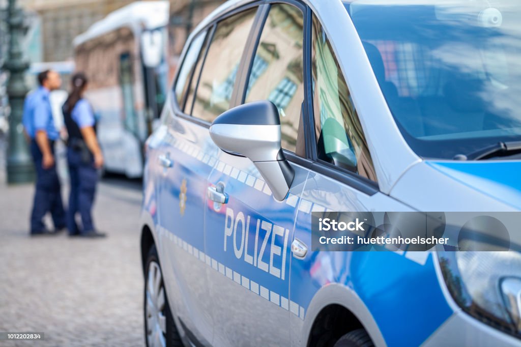 German police car stands on street. Two police officers controls traffic. Polizei is the german word for police Police Force Stock Photo