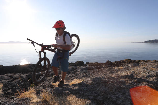 istock Mountain biker carries bike over difficult terrain 1012205712