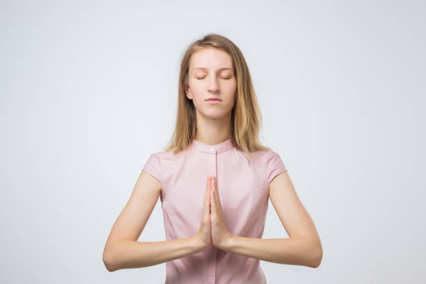 istock European casually dressed young woman keeping eyes closed while meditating 1012208654