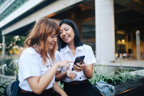 young asian students in uniforms sitting in front of the university - adult student college student school uniform student imagens e fotografias de stock