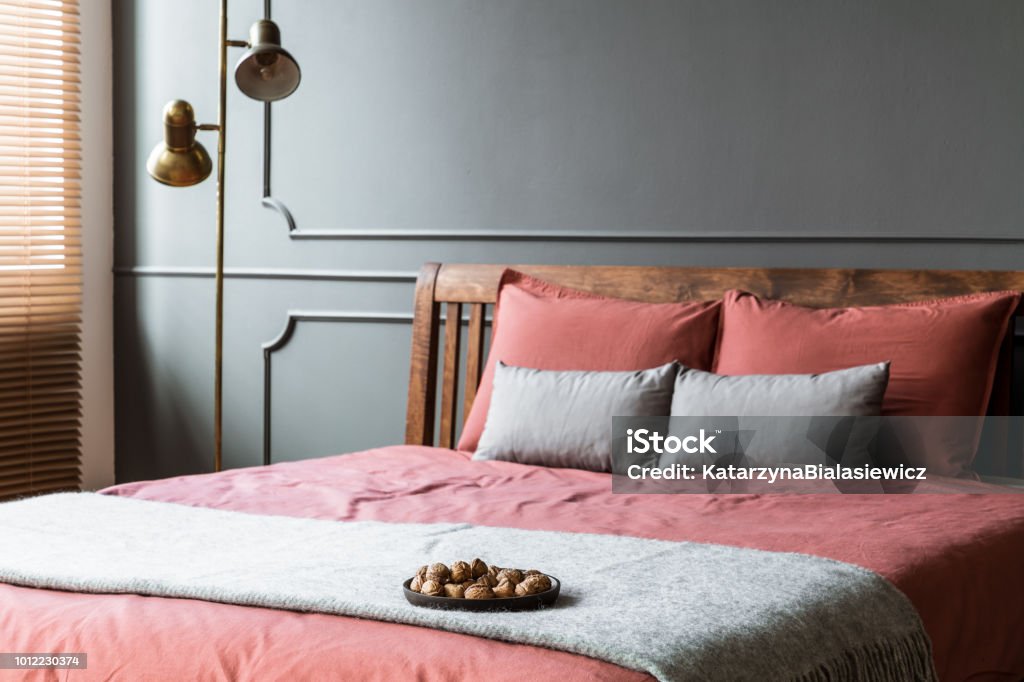 Close-up in hotel bedroom interior Close-up of grey blanket on pink bed in hotel bedroom interior with gold lamp Apartment Stock Photo