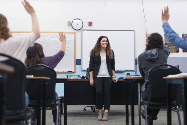 istock Ethnic teacher smiles while she waits to call on students with raised hands 1012230602