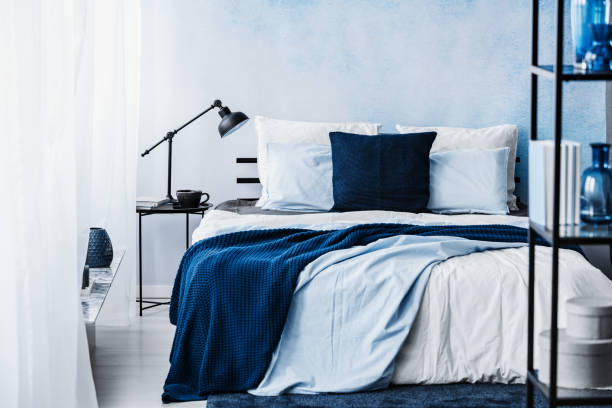 istock Navy blue blanket on bed in pastel bedroom interior with lamp on table 1012238068